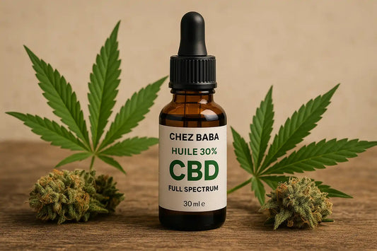 Bouteille d’huile de CBD 30% full spectrum Chez Baba posée entre deux têtes de fleurs de cannabis et des feuilles de chanvre sur fond naturel.